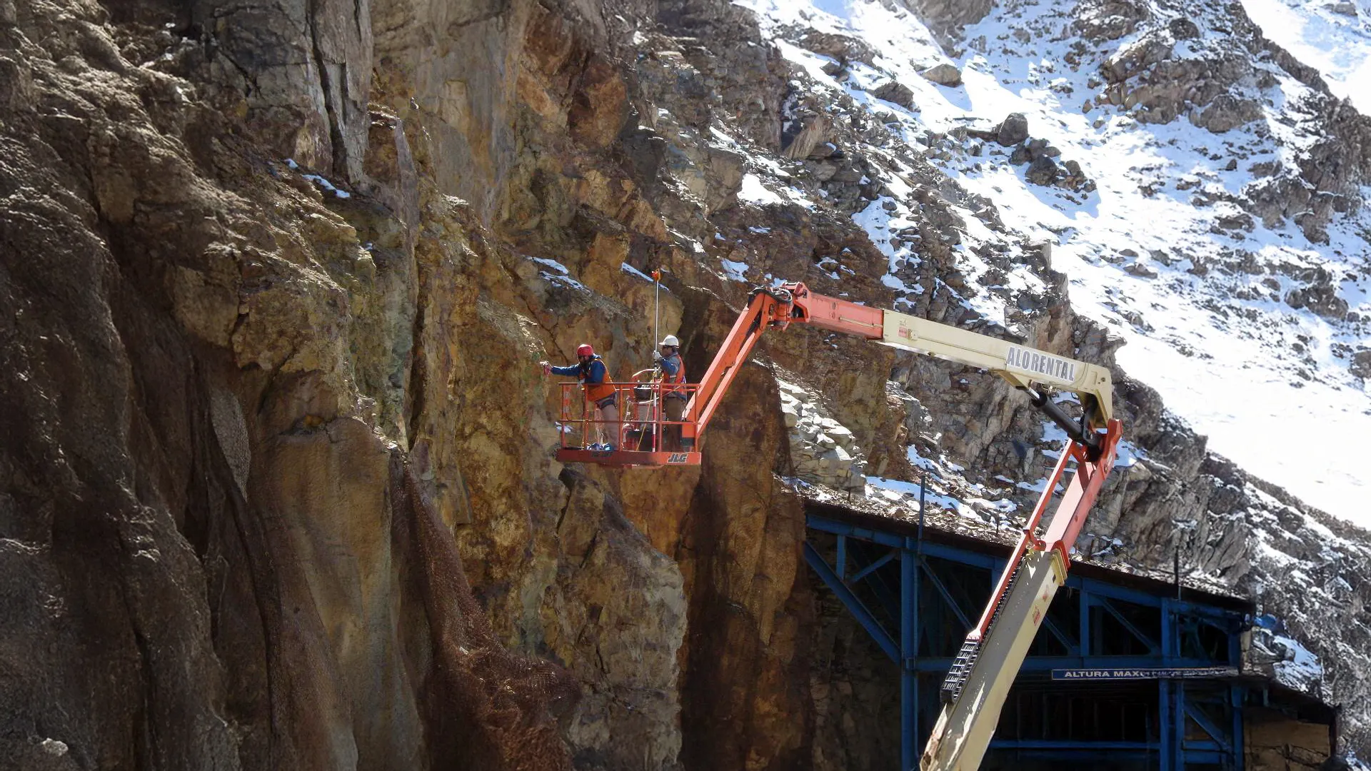 Inspección geológica en pared rocosa nevada con plataforma elevadora, conforme a estándares ambientales y de seguridad