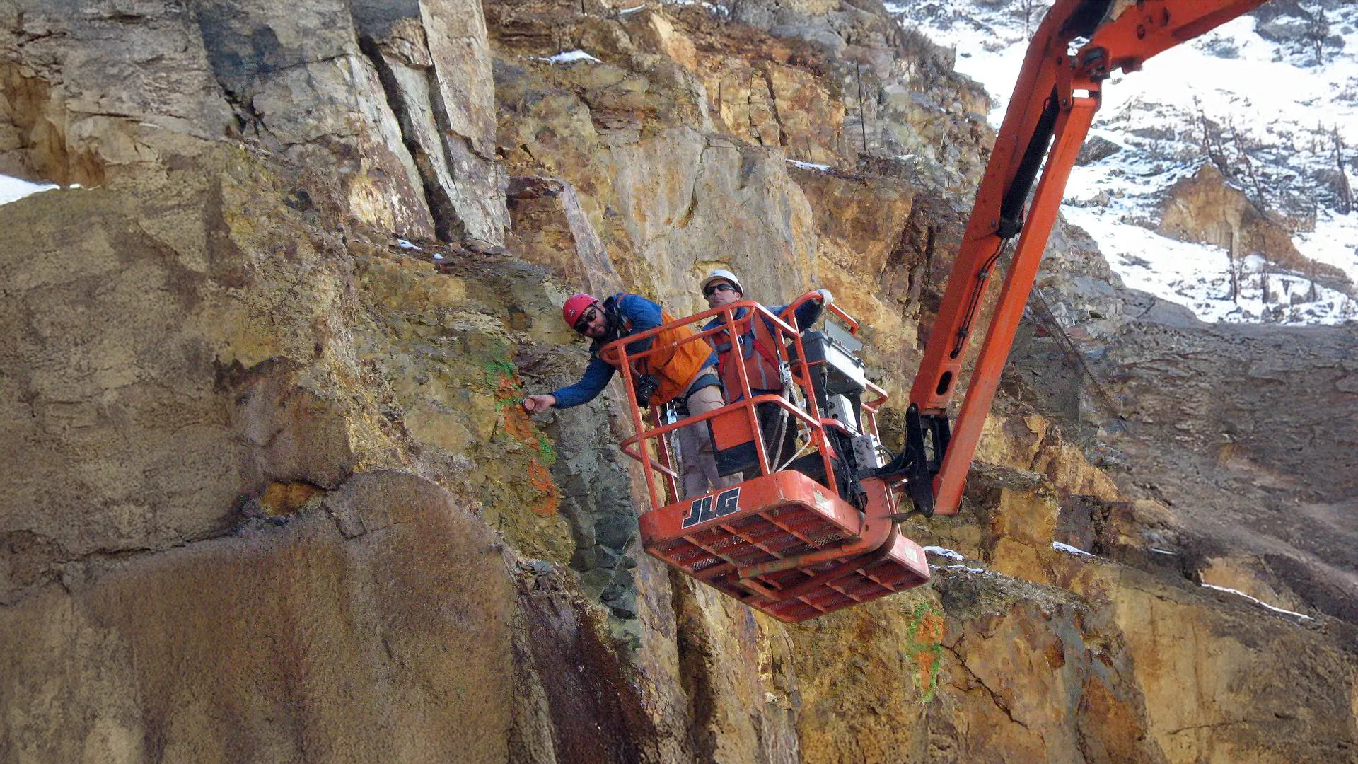 Inspección geológica en pared rocosa desde plataforma, vinculada a evaluación de recursos geológicos y riesgos ambientales