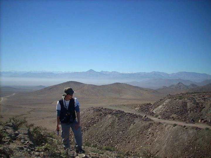 Especialista realizando prospección paleontológica e inspección visual en extensa zona desértica.